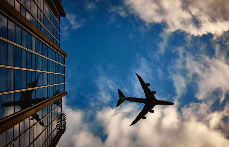 Passenger aircraft passing above the glass terminal building at Edinburgh Airport