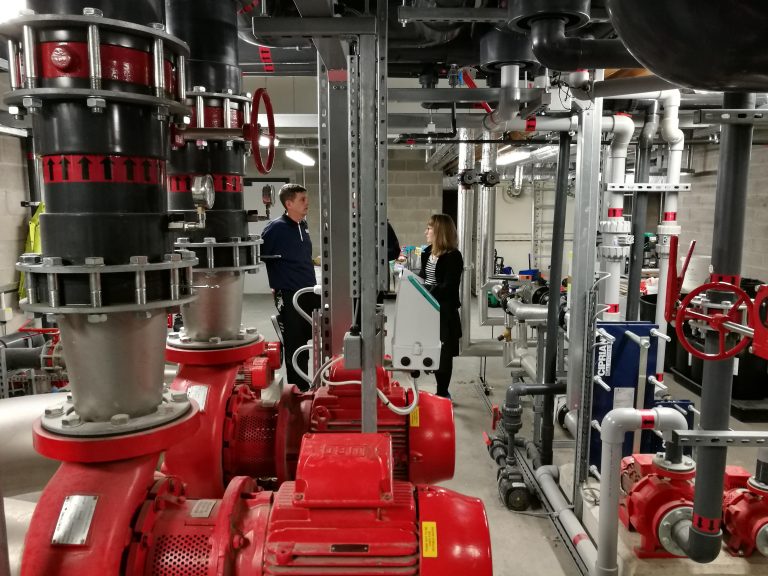 Large red circulation pumps and pipework in a heat network plant room
