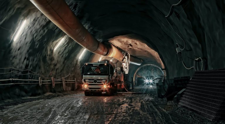 Lorry driving through a lit underground tunnel in a working mine